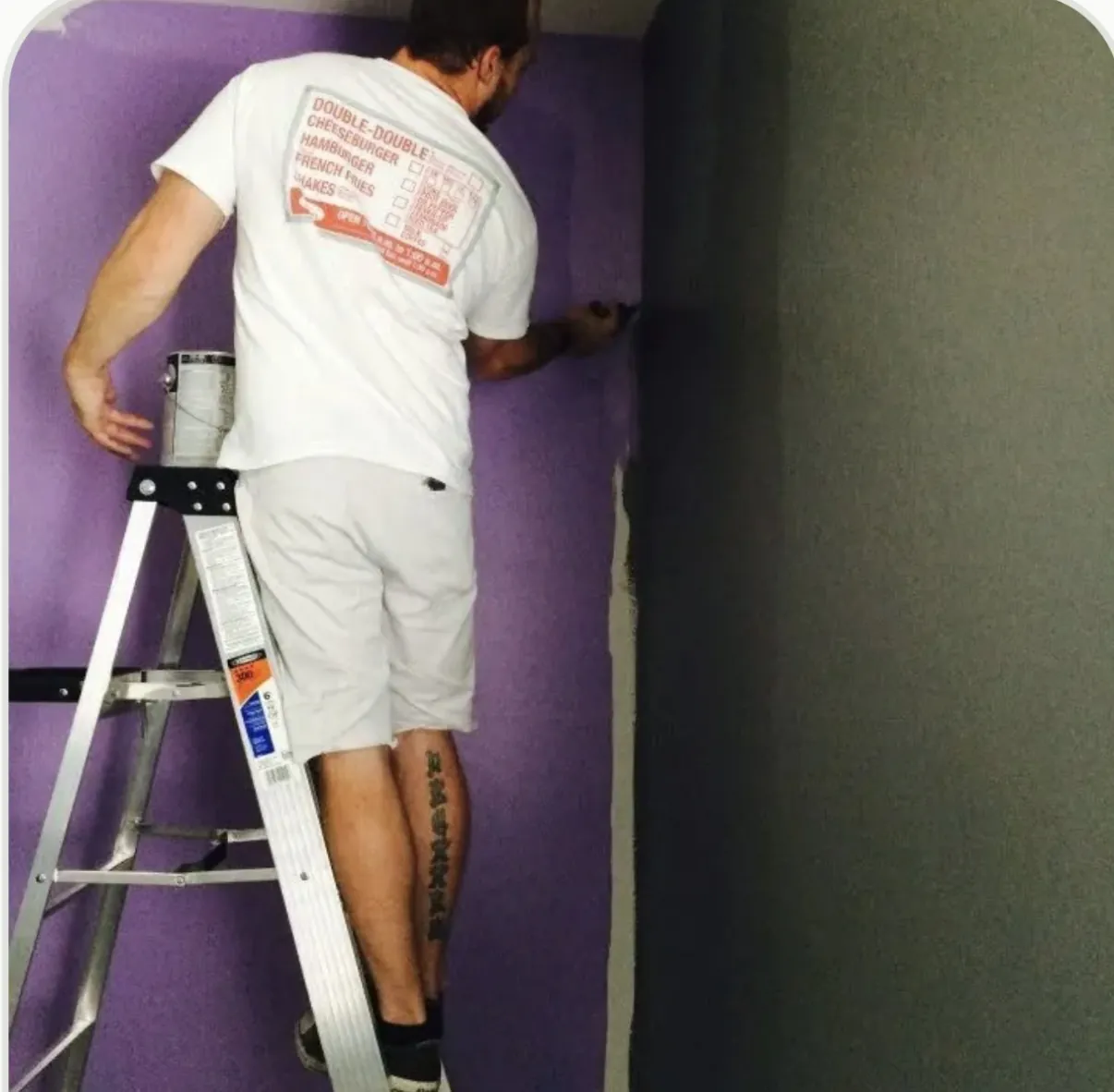 MK Painting crew member cutting in a crisp paint line between a purple accent wall and adjoining wall in a Las Vegas home
